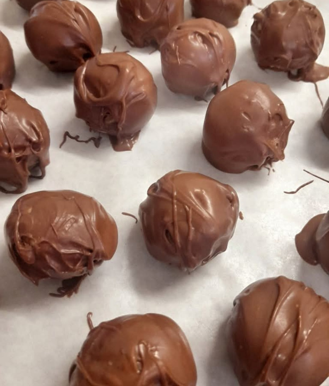 Kai's Sweet Co handmade Chocolate Coated Cookie Dough Balls freshly dipped and cooling on baking paper, made in small batches