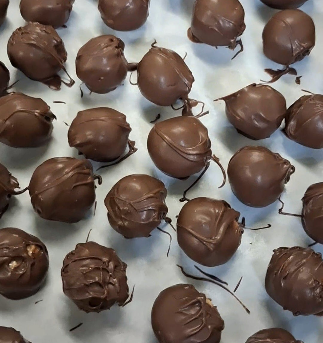 Kai's Sweet Co Mini Chocolate Coated Cookie Dough Balls freshly dipped and cooling on baking paper, handmade in small batches