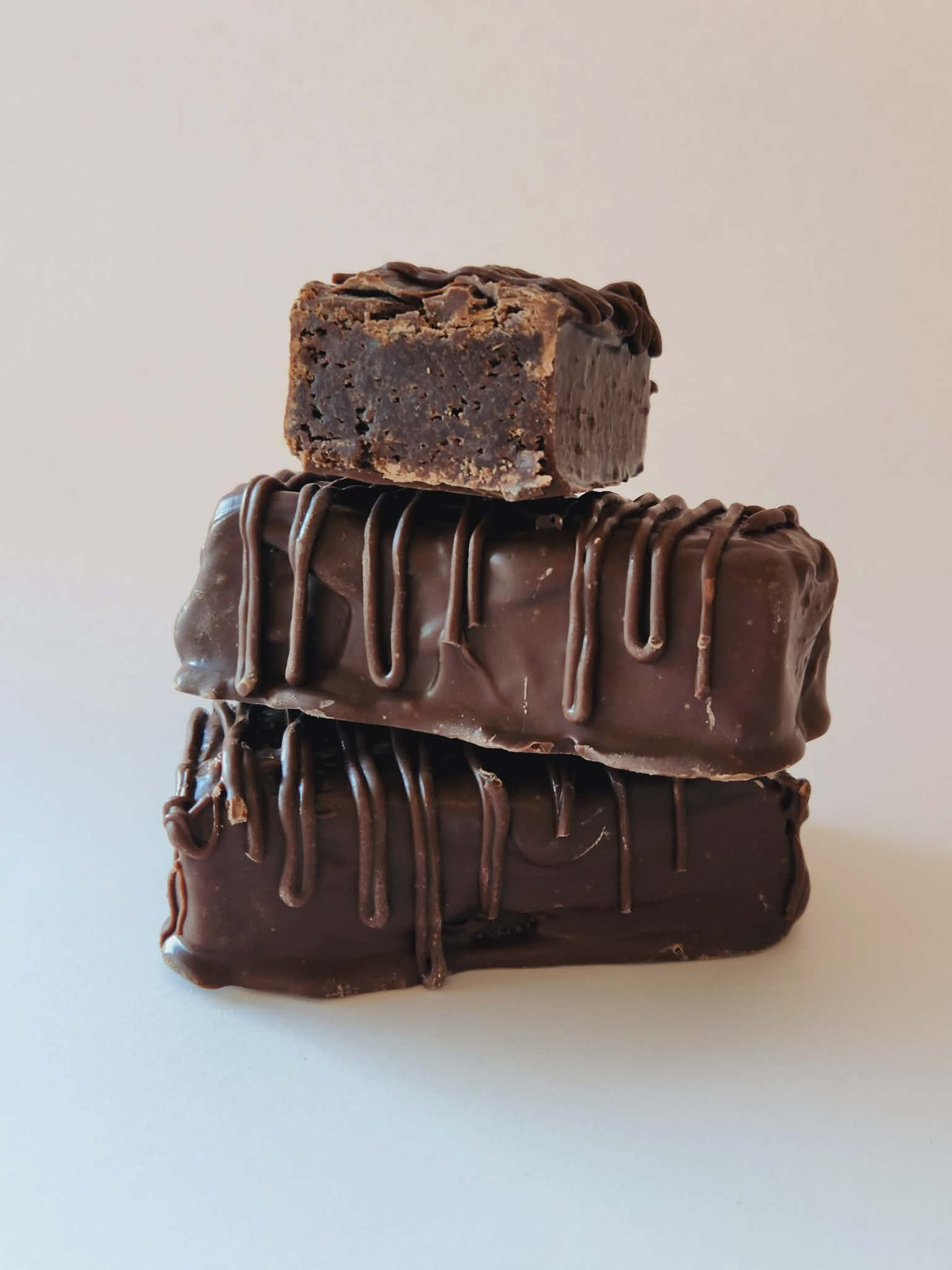 Kai's Sweet Co Chocolate Fudge Brownie Bars stacked three high with chocolate drizzle, handmade and chocolate coated