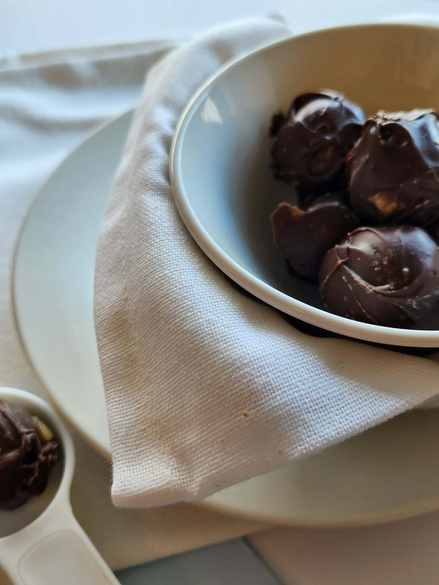 Kai's Sweet Co Mini Chocolate Coated Edible Cookie Dough Balls served in a white bowl with linen napkin, handmade sweet treat